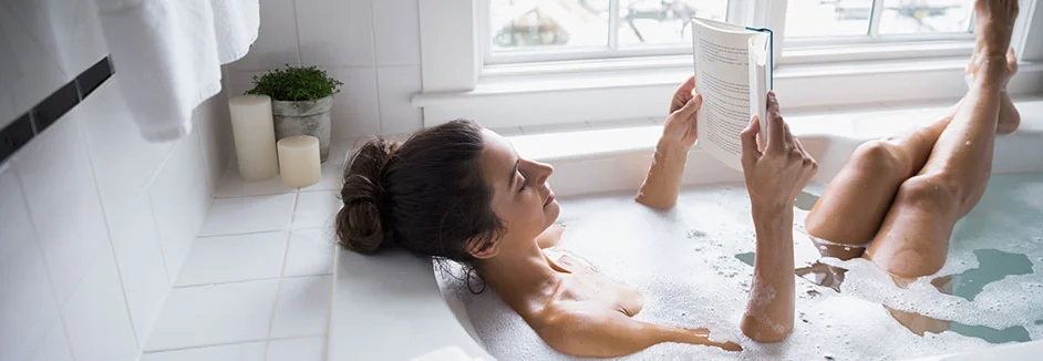 Person liest in der Badewanne ein Buch.
